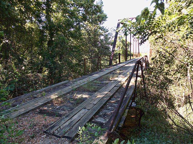 Wooden platform on steel truss bridge with trees around it