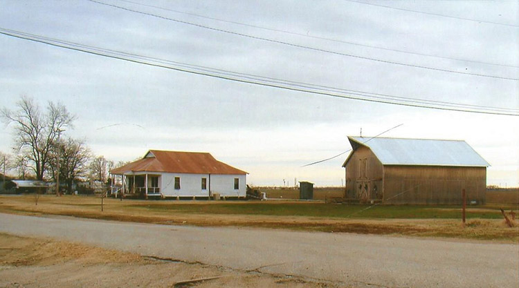 Single-story house with rusted metal roof outbuilding and barn