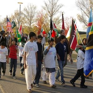 Mixed group of adults and children marching with flags of various nations on street