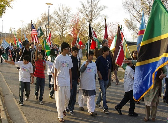 Mixed group of adults and children marching with flags of various nations on street