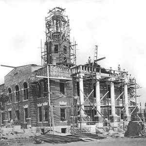 Workers working on brick courthouse with tower