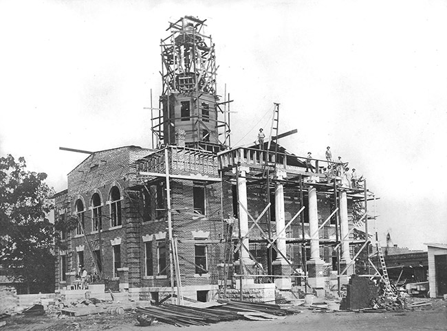 Workers working on brick courthouse with tower