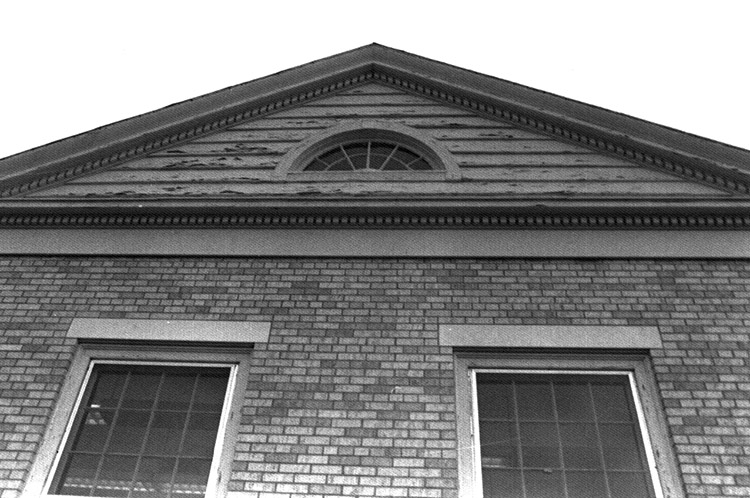 Close-up of brick building with semicircle roof window