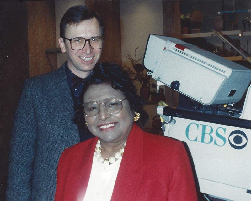 White man and African American woman in front of television equipment