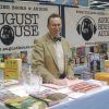 White man in bow tie standing amid displays of books
