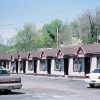 Single-story motel building with identical apartments with pink trim and cars in parking lot