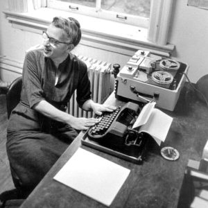 White woman in glasses using a typewriter