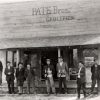 Group of white men standing outside "Pate Bros." grocery store