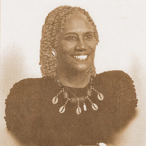 African-American woman smiling in dress and shell necklace