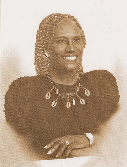 African-American woman smiling in dress and shell necklace
