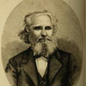 White man with long beard in suit and bow tie with signature below his image