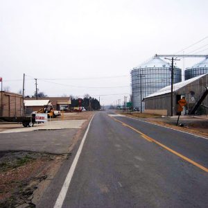 Street with two large silos on the right and buildings on the left