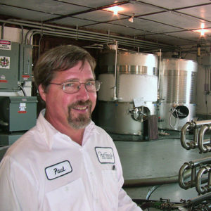 White man with glasses and beard in white shirt standing in tank room