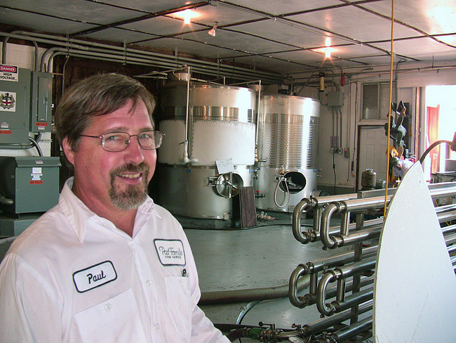 White man with glasses and beard in white shirt standing in tank room