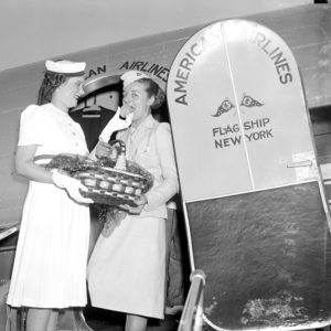 Two white women boarding airplane, one holding basket of peaches