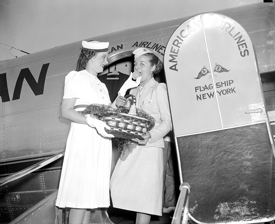 Two white women boarding airplane, one holding basket of peaches