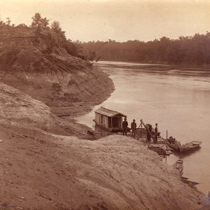 Four men on river dock with cabin barge and small boats