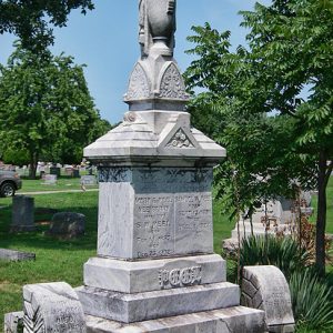 Tall stone grave marker with urn on top in cemetery