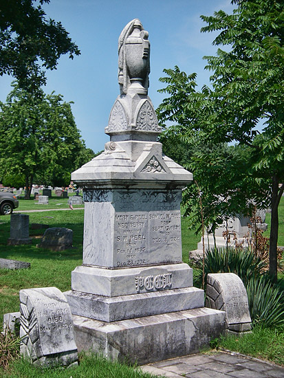 Tall stone grave marker with urn on top in cemetery