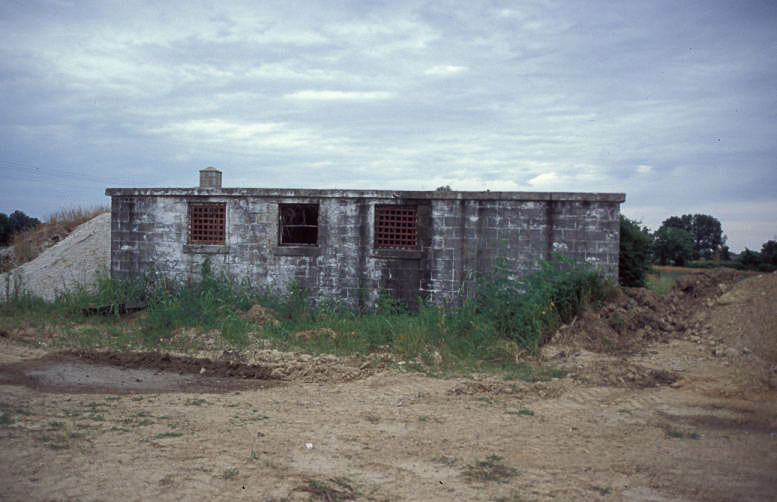 low brick building with bars on its windows on dirt road