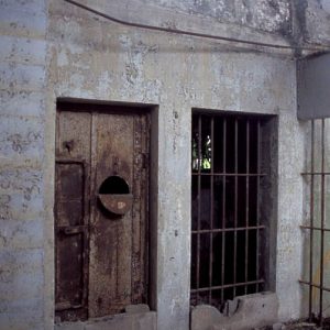 Cell door and bars inside ruins of concrete cell block building