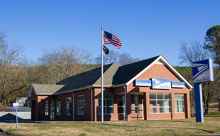 Single-story brick building with sign and flag pole