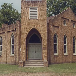 Brick church building with central tower with gothic arch entrance