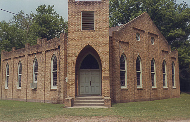 Brick church building with central tower with gothic arch entrance