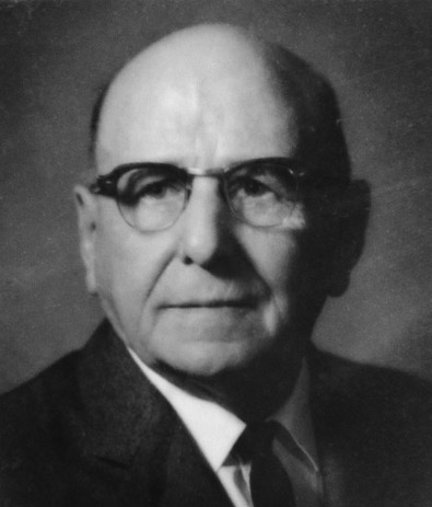 Bald white man with glasses in suit and tie