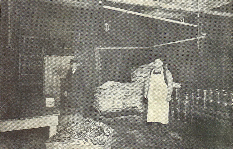 White man in apron and white man in suit in meat processing plant