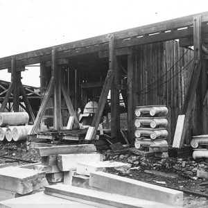 Stacks of marble column pieces and cut stone outside wooden quarry building