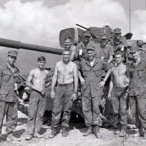 Group of young white men in military uniform and shirtless posing with tank