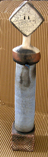 Clay cylinder with diamond shaped object on top of it