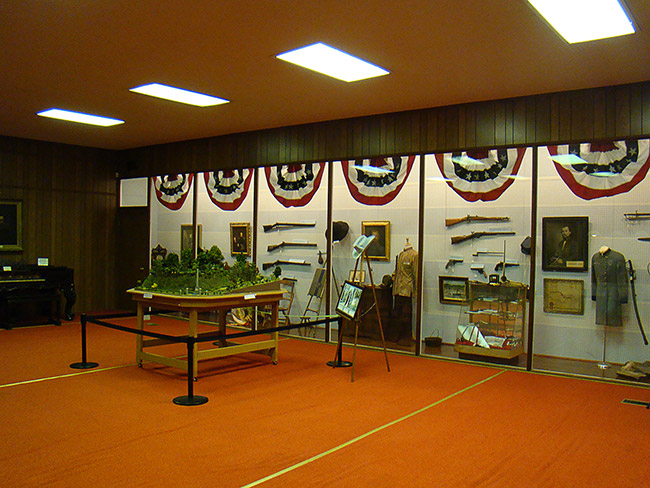Interior of museum with guns and military artifacts behind glass