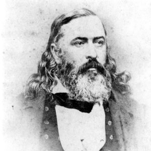 Large white man with long curly hair and beard in suit and bow tie