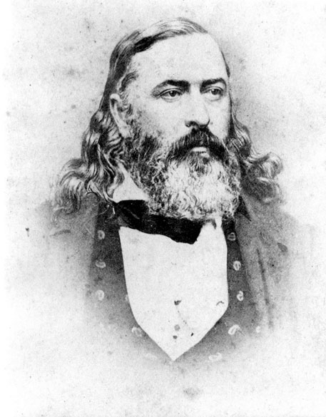 Large white man with long curly hair and beard in suit and bow tie
