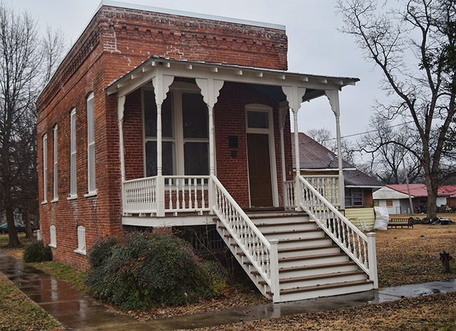 Close-up on brick building with covered porch and stairs