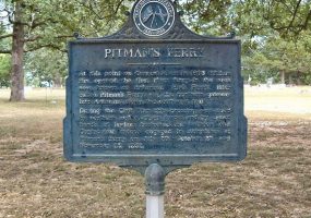 Weathered "Pitman's Ferry" historical marker sign in front of trees
