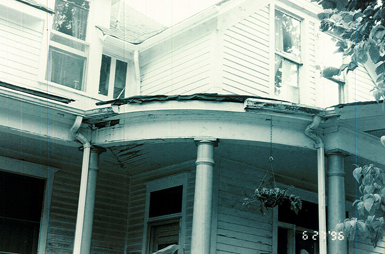 Close-up of multistory house with damaged porch roof