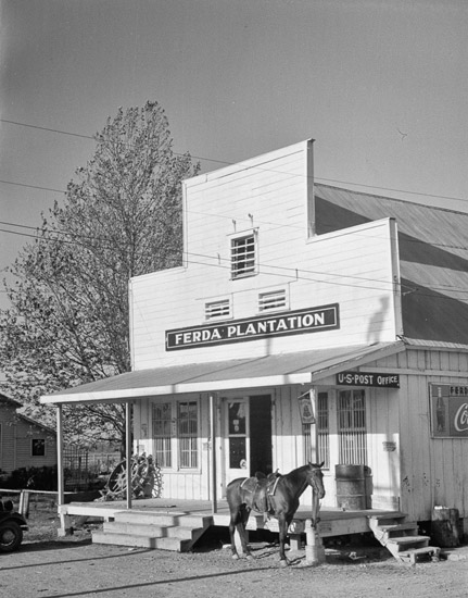 store building with tall front with "Ferda Plantation" sign over covered porch with horse in front