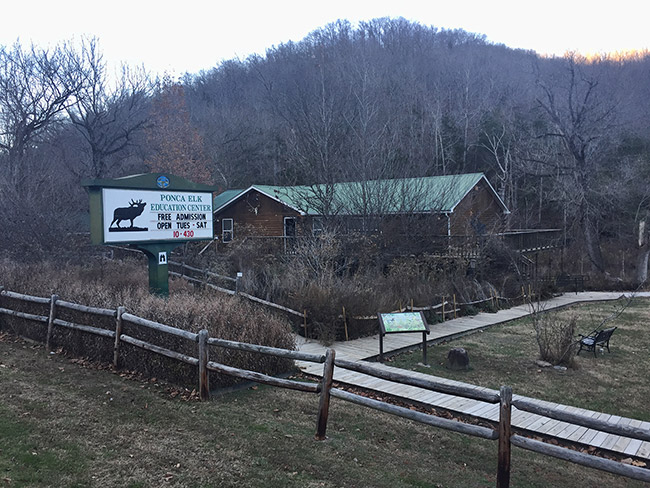 Single-story building with deck wooden fences and sign with Elk logo by walking path
