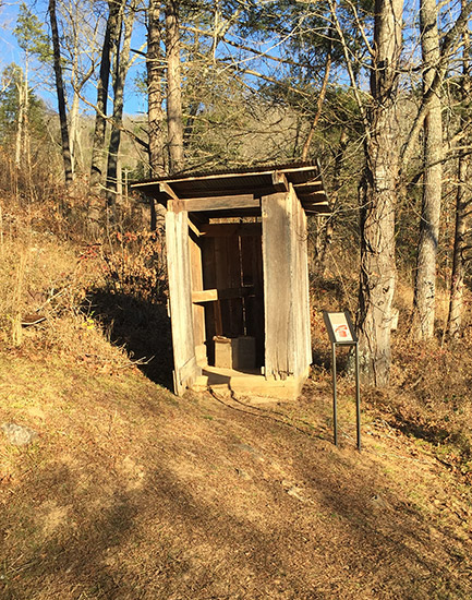 Outhouse with sign in woods