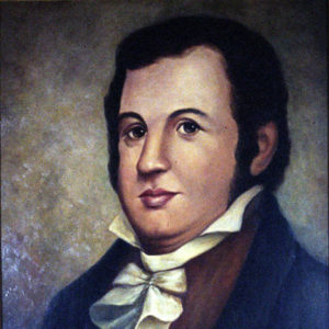 White man with dark hair in a blue suit and white cravat