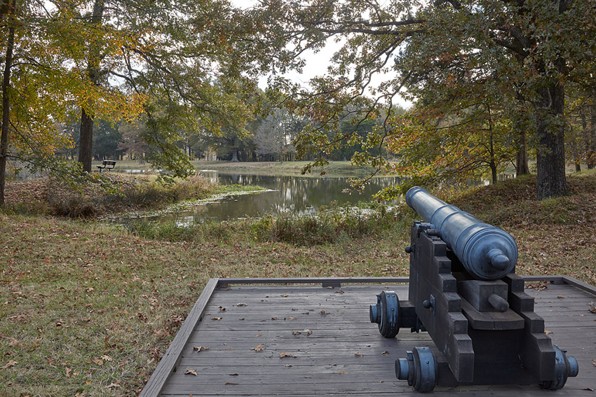 Cannon on wooden platform pointed over body of water