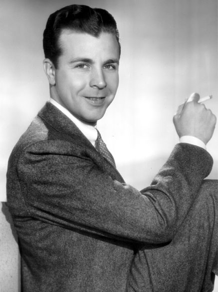 White man in suit and tie holding a cigarette
