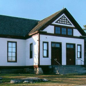 Single-story building with white siding framed windows and two front doors on steps