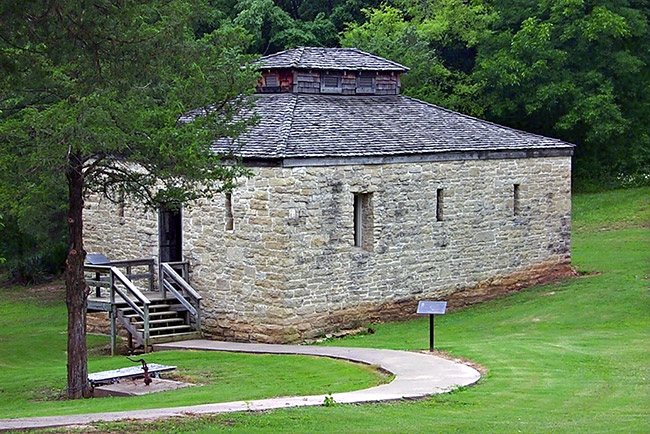 Stone jail building with narrow windows, walkway and wooden steps