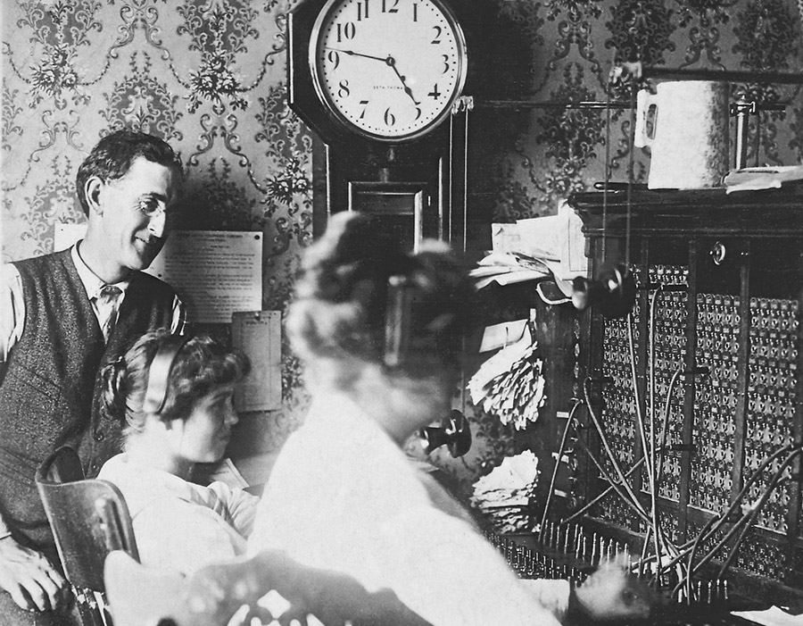 White man with glasses in suit with white female switchboard operators at work