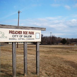 "Preacher Roe Park" sign with baseball field and lights in the background