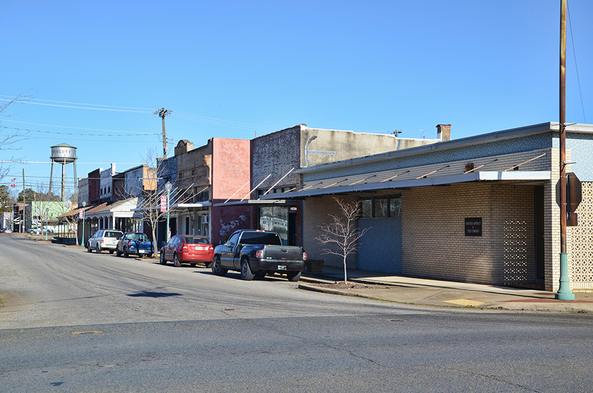Two-story storefronts on street with water tower in the background